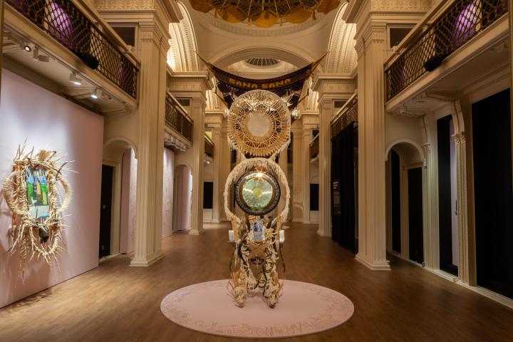 A large sculpture made from natural materials stands in a gallery space