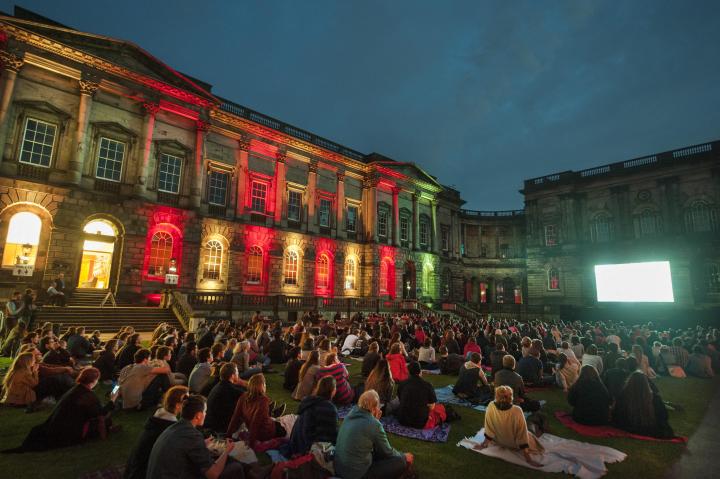People sitting on Old College Quad to watch outdoor cinema 