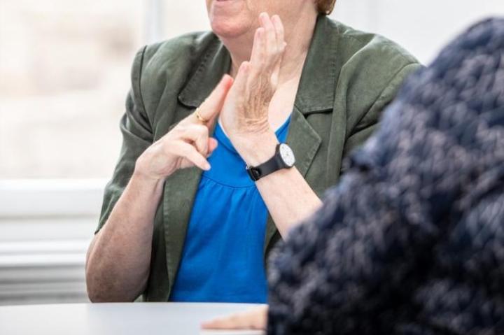 A lady is signing the letter N in British Sign Language
