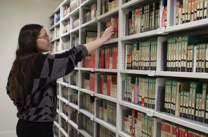 a woman getting a book from a bookshelf