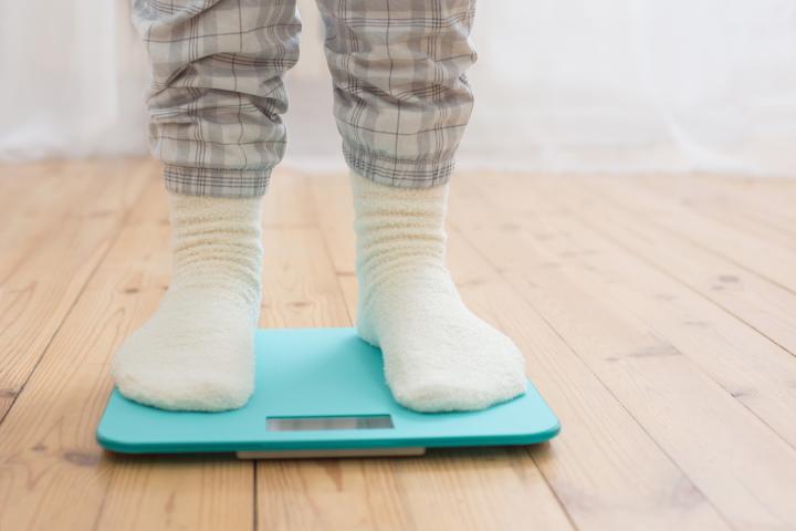 Female legs on electronic scales on wooden floor