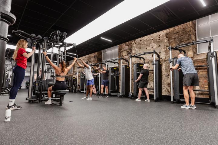 A large well-lit gym is filled with state-of-the-art equipment being used by people in active wear