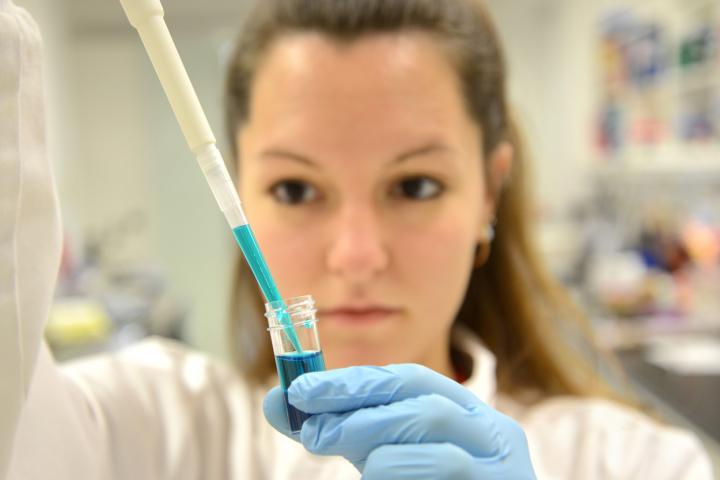 Closeup of scientist pipetting a substance into a dish