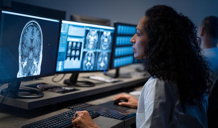 Side view of female radiologist looking at an MRI image of the brain on her computer