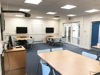 A tutorial room with 4 workstations - desk, chairs and a computer.