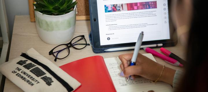 Student taking down notes in front of tablet