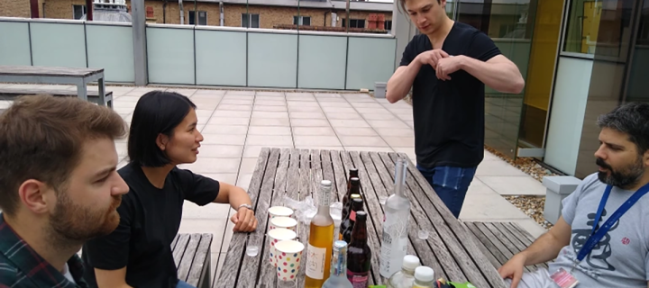 Photo of the lab group seated at a table outside a building