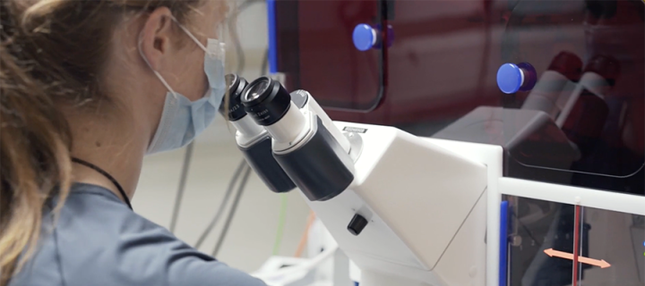 Photo of lab worker looking into microscope