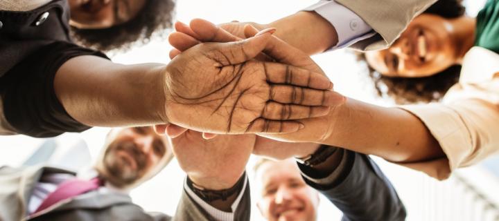 People smiling with hands joined in the centre