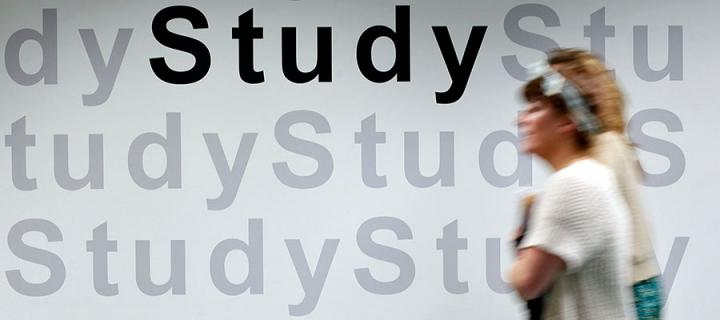 Woman walking past Study sign