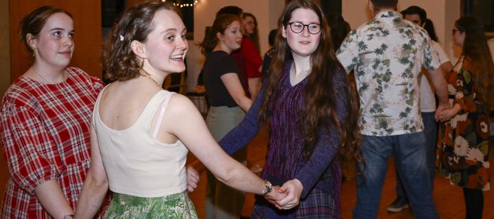 Students holding hands in a circle at ceilidh. 