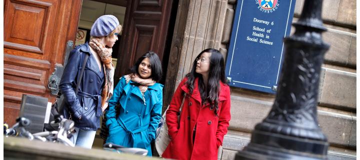 three students stand in front of a University building
