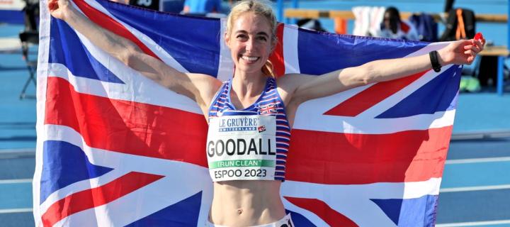 Alice Goodall holding a Union Jack flag after a race