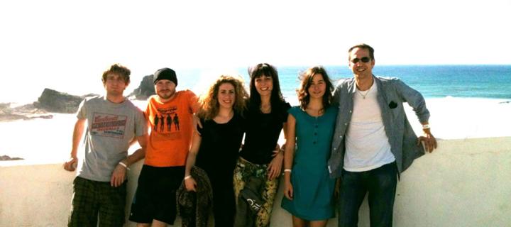 Lab group members pose for a group photo in front of a wall overlooking the sea