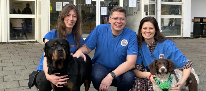 K9-LiquiDX team pictured kneeling on floor outside vet clinic with two dogs