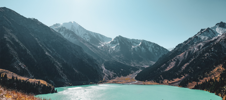 Mountain in the daytime with snow and a bright blue lake