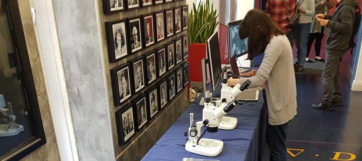 Researcher setting up indoor engagement event with microscopes on tables