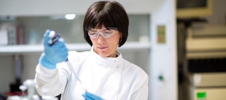 A researcher with protective eyewear using a pipette