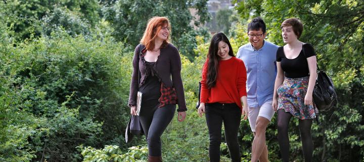 Students relaxing in the Royal Botanic Garden with Edinburgh city centre and the Pentland Hills in the background.