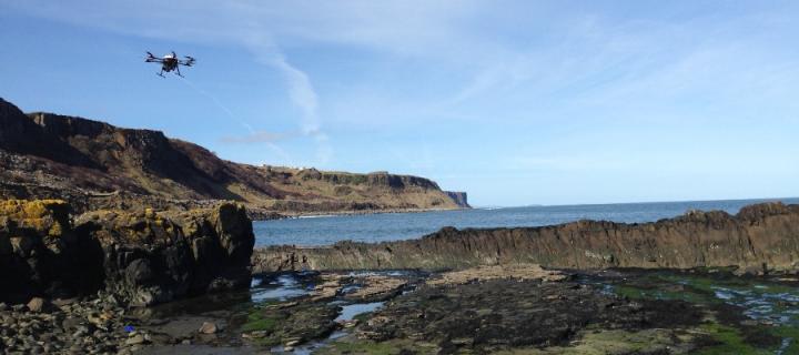 A drone flying over rocks next to the sea edge at Skye, Scotland
