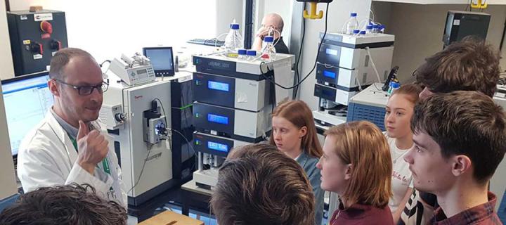 Researcher in lab talking to group of youg people