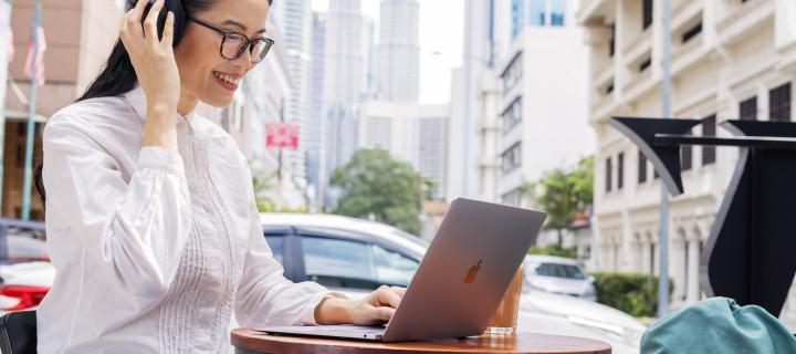 Female student using laptop while wearing headphones in Kuala Lumpur