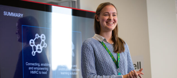 Graduate Veronika Pudilova giving a presentation in front of a plasma screen