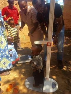 Photo of a toddler being measured by two health care workers