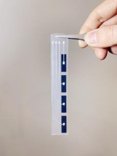 Image of a section of e-skin being held with tweezers