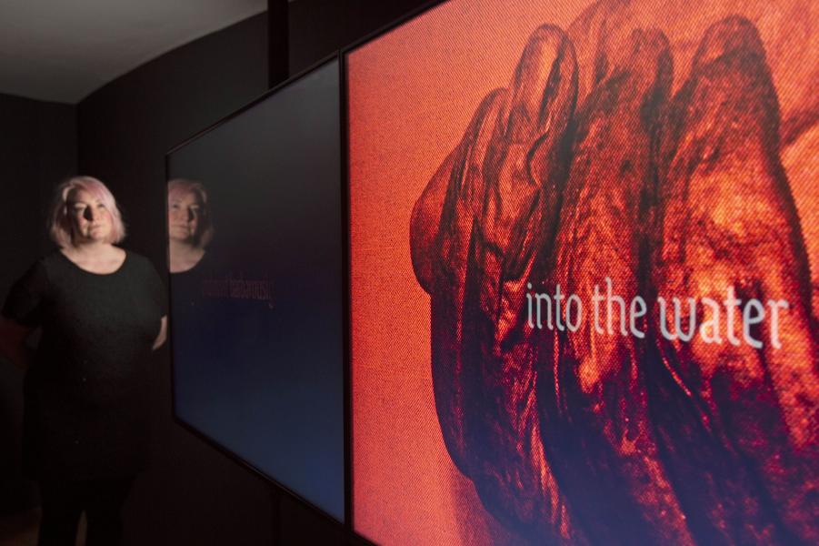 A person stands at two screens looking at pieces of art by artist Aideen Doran