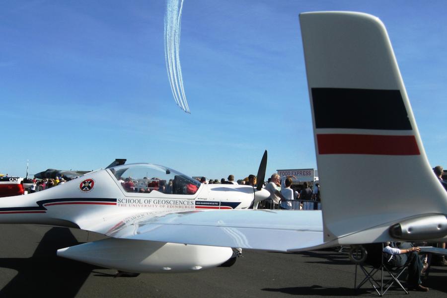 Dimona aircraft on ground display at an airshow with red arrows above