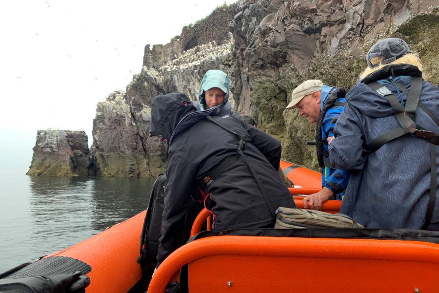 film crew exiting a small boat onto the bass rock