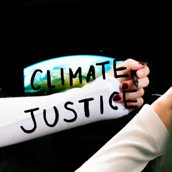 arm held up to mirror - words climate justice written on mirror