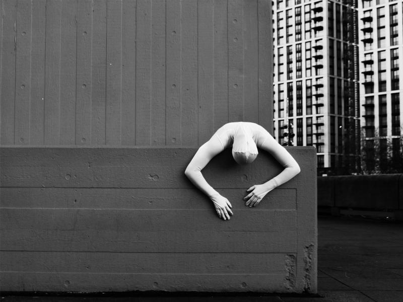 industrial setting, person head to toe in white suit, draped over wall
