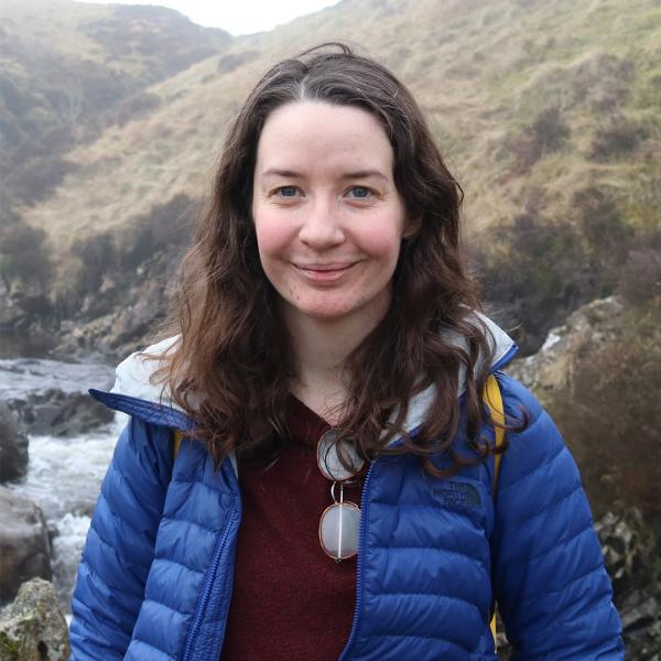 Claire Hobday smiling in front of outdoor scenic background.