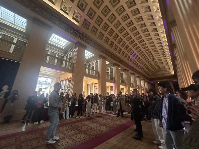 A saxophonist performs at Playfair Library in front of an audience of postgraduate students