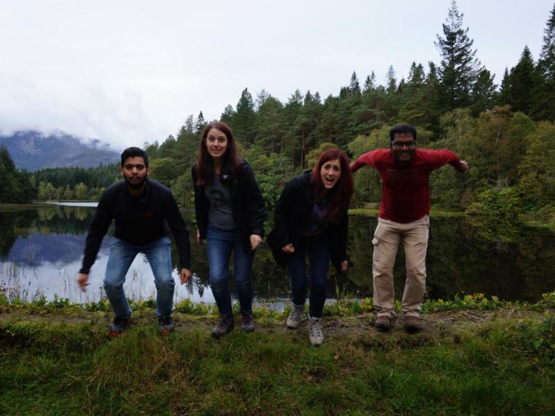 Lab group members stand by the edge of a lake surrounded by trees