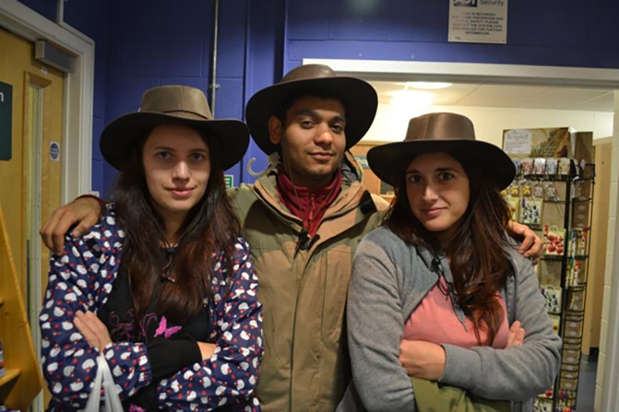 Three lab goup members pose for group photo indoors, they wear stetson hats
