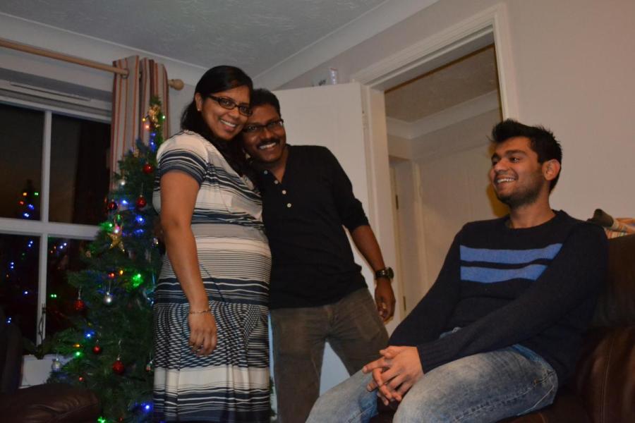 Jp and partner with lab group member pose for photo in a house with Christmas decorations
