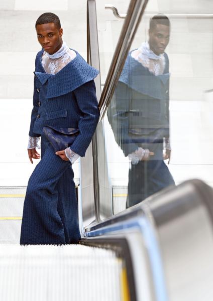 A model poses on an escalator in a blue outfit