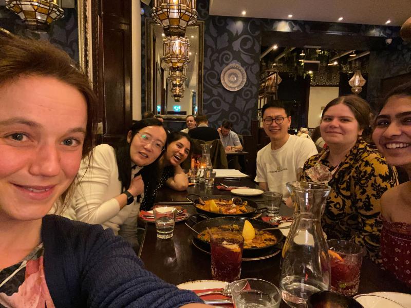 Group photo with lab group members sitting around a table with food and drinks