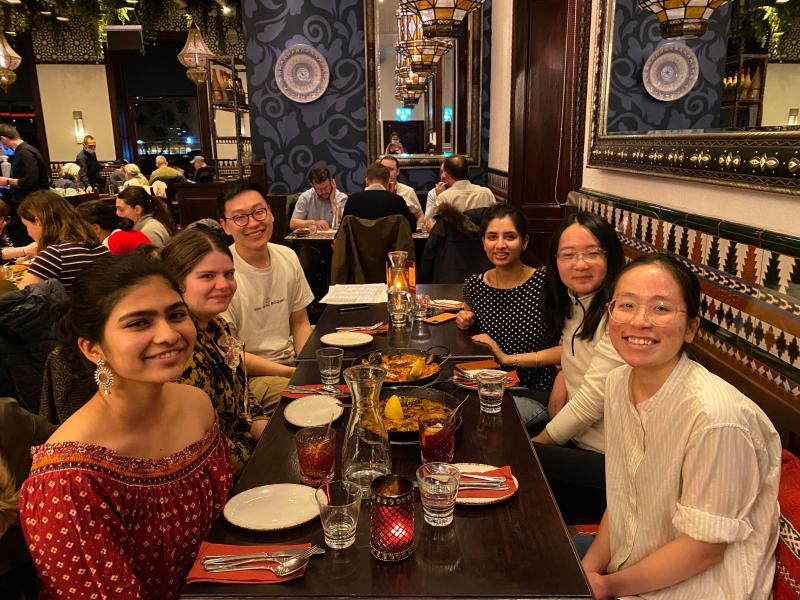 Group photo with lab group members sitting around a table with food and drinks