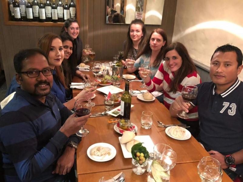 Group photo, all members sitting around a table with food and drink