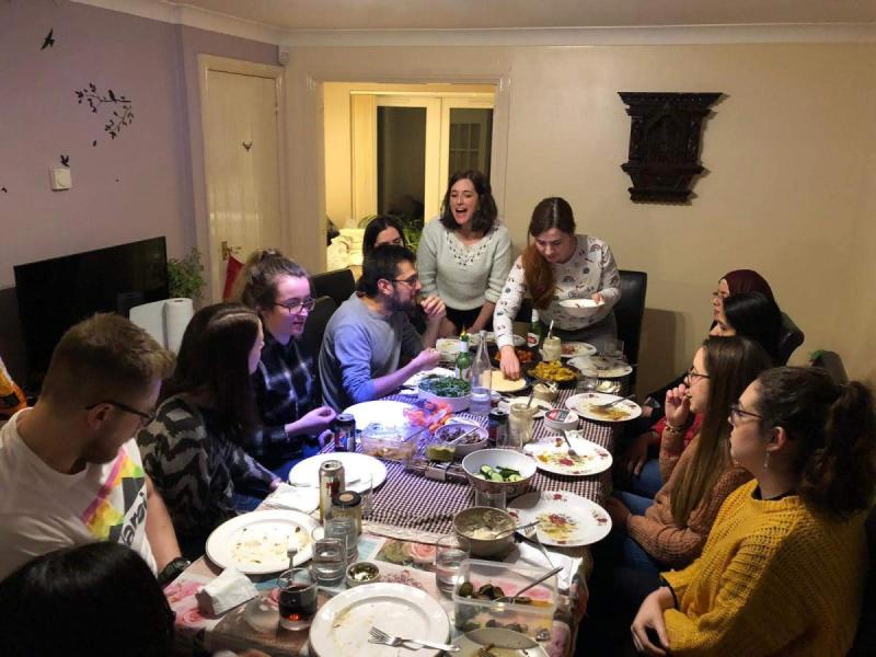 Photo of the group members sat around a large dining table eating pancakes