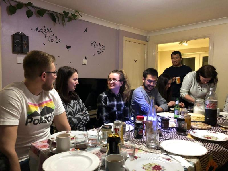 Photo of the group members sat around a large dining table eating pancakes